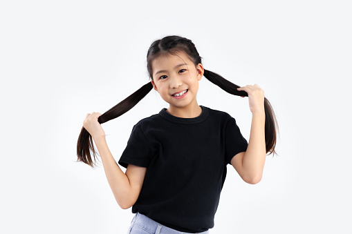 Asian kid long hair in black t-shirt posing happy on white background.