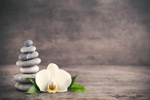 Spa stones and white orchid on the grey background.