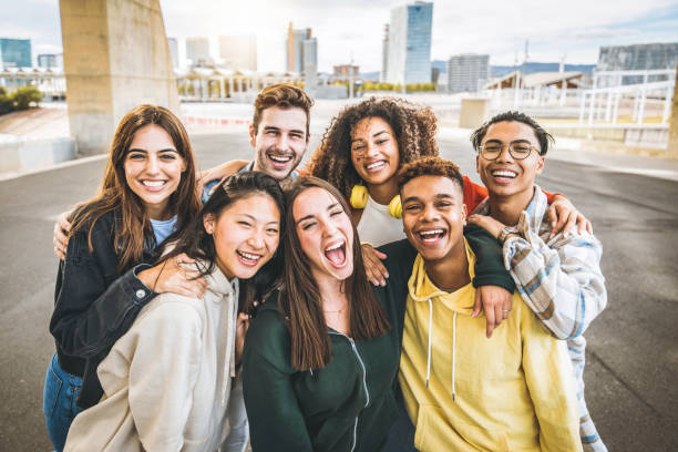 Multiracial group of friends taking selfie picture outdoors - Millennial people having fun on city street - International students smiling together at camera - Youth culture and community concept stock photo
