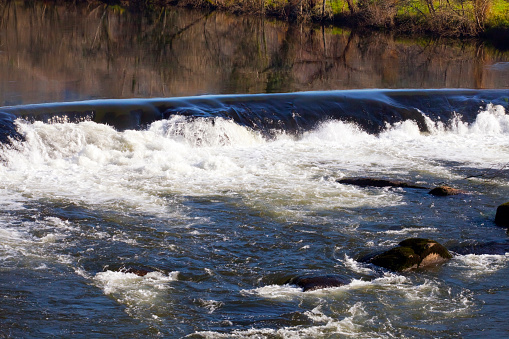 Tambre River passing by Ponte Maceira  village, A Coruña  province, Galicia, Spain. Camino de Santiago. Flowing river ,small waterfall, rocks and reflections in Galicia, Spain.