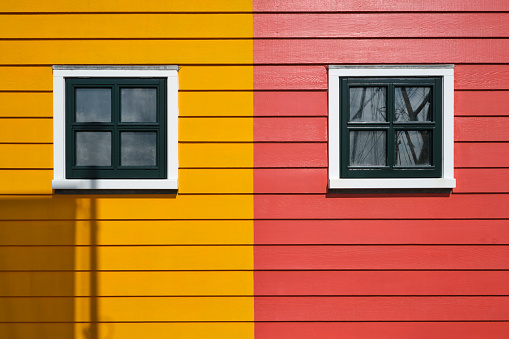 Detail photo of painted wood and windows of some Scandinavian like colored houses in Zoutkamp, The Netherlands. Red and yellow abstract geometric image.