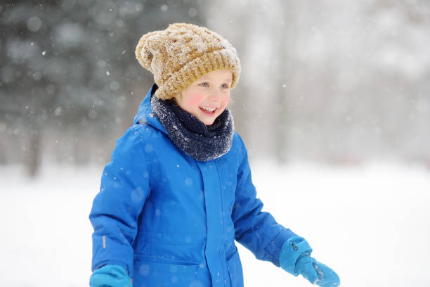 istock Little boy having fun playing with fresh snow during snowfall. Baby catching snowflakes on gloves. Kid dressed in warm clothes, hat, hand gloves and scarf. Active winter outdoors leisure for child 1431316066