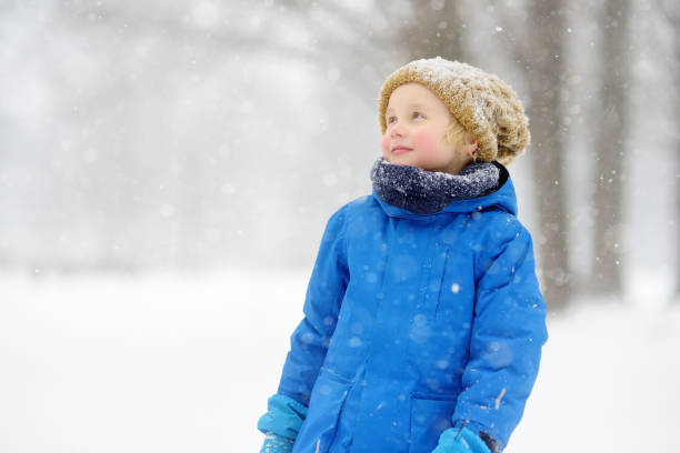 istock Little boy having fun playing with fresh snow during snowfall. Baby catching snowflakes on gloves. Kid dressed in warm clothes, hat, hand gloves and scarf. Active winter outdoors leisure for child 1431316506