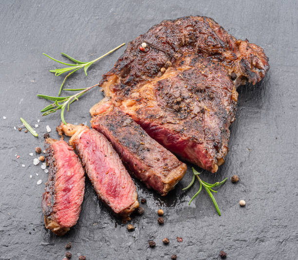 istock Grilled medium rare ribeye steak on gray stone plate. 1431317044