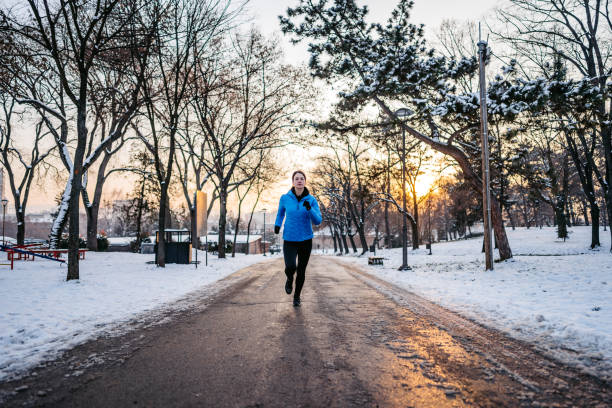 Beautiful young woman jogging in a snowy park during winter.
