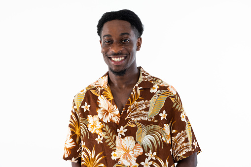 Happy handsome man looking at camera smiling laughing wearing colorful shirt printed with flowers standing on white background isolated in studio.