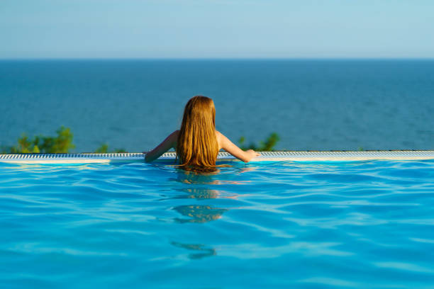 istock rear view. A woman by the side of a panoramic pool 1431318633