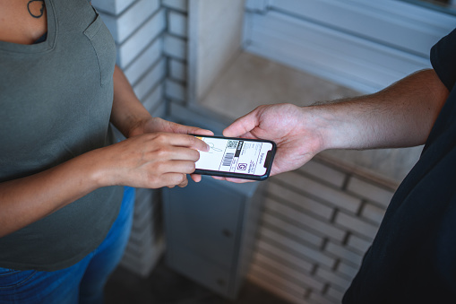 Young delivery man  standing in front of house entrance, only his arms visible,talking to the client, who is confirming the arrival of package with her signature.