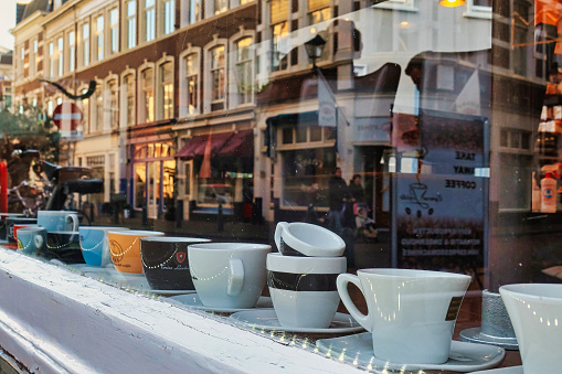 Den Haag, Netherlands - January 10 2022: espresso cups at put for decoration in the window of an espresso bar with reflections of a dutch street