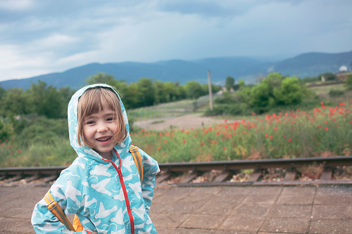 Little child waiting for a train in rainy and gloomy day.