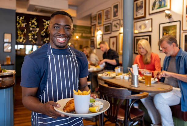 istock Happy waiter serving food at a pub 1431332801