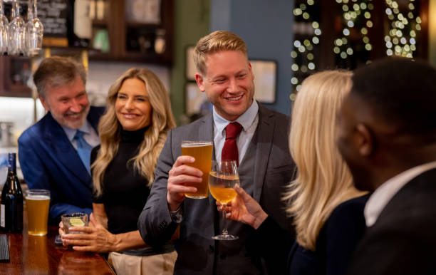 Coworkers drinking at the pub and making a toast Happy group of coworkers drinking at the pub and making a toast - lifestyle concepts occasional drink stock pictures, royalty-free photos & images