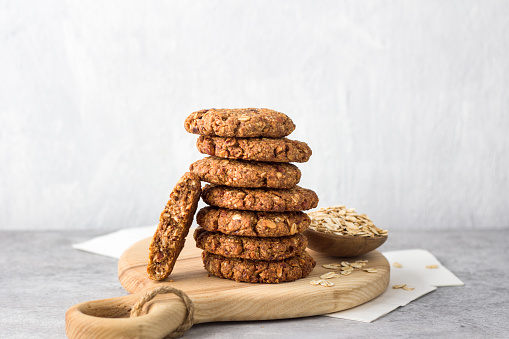 Healthy oatmeal cookies with dates, nuts and flaxseed on a wooden board on a gray textured background. Delicious homemade vegan food