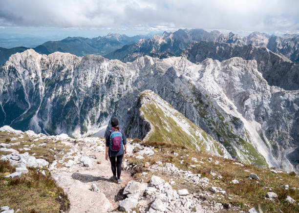 istock A girl with backpacks walking down a mountain path. 1431335551