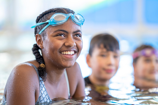 Group of multicultural kids taking swimming lessons at a recreational centre.