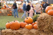 Pumpkins on straw bales against the background of people at an agricultural fair