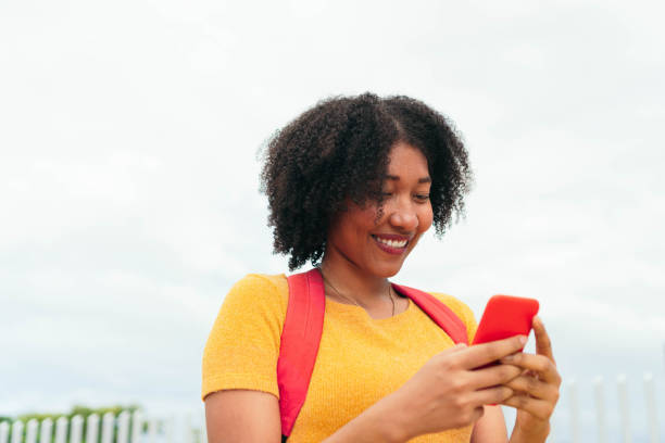 istock Mixed-race woman using a smartphone walking on the street 1431337455