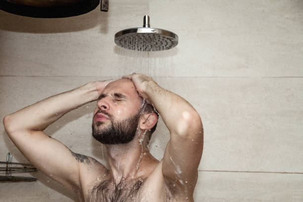 istock Portrait handsome young guy taking shower washing, standing under falling water in bathhouse or sauna. Man body care beauty routine and everyday hygiene concept. Copy text space 1431346172