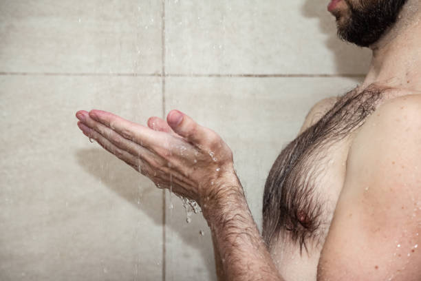istock Close up hands young bearded man taking shower in bathhouse (sauna) under water falling from rain shower head. Morning lifestyle guy showering. Concept body care hygiene. Copy text space 1431346178
