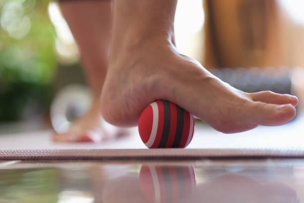 persona rotola palla a piedi a casa primo piano - reflexology human foot physical therapy massaging foto e immagini stock