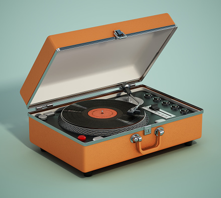 Portable analogue record player or turntable on green background.