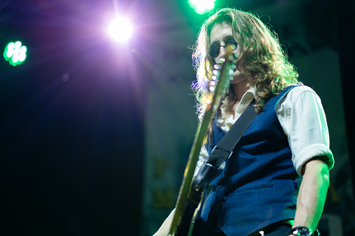 Caucasian ethnicity young adult man with long hair playing electric guitar