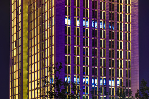 In the night, the decorative lights on the exterior wall of the building are colorful, and the windows are lit. People who work overtime may still be working