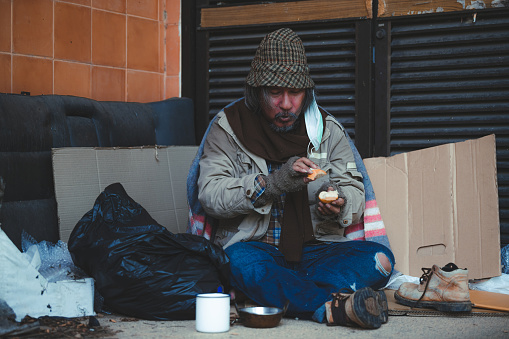 Color image depicting the rear view of a homeless man begging for money in central London, UK.