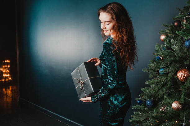 istock Beautiful girl with present box near Christmas tree 1431351363