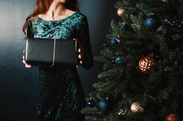 istock young woman with gift box near Christmas tree 1431352592