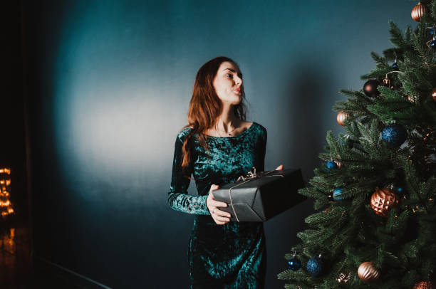 istock Beautiful woman holding a gift box near Christmas tree 1431353053