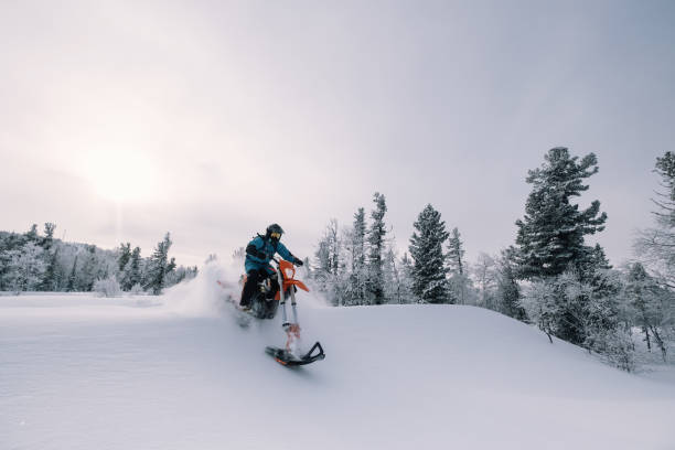 美しい雪の粉の山の谷でスノーバイクライダー。雪の水しぶきとトレイルでダートバイクを修正します。スノーモービルスポーツライディング、冬晴れの日 - snowmobiling snow winter mountain ストックフォトと画像