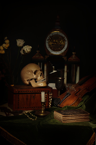 Close-up still life, Dutch painting of the 17th century. On the table on a black background are flowers, a skull, a clock, a violin, keys. Things that tell about a person's life.