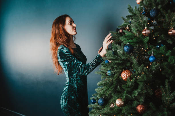 istock Beautiful brunette woman decorating Christmas tree 1431354666