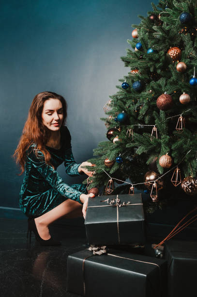 istock Beautiful female sitting next to Christmas tree with gift boxes 1431355391