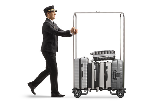 Bellboy pushing suitcases on a hotel luggage cart