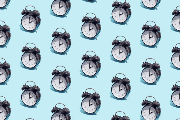 istock Seamless pattern of black retro alarm clocks  show 2 o'clock. Changing clock from summer time to winter time. Shifting the clock hands back in autumn. 1431357987