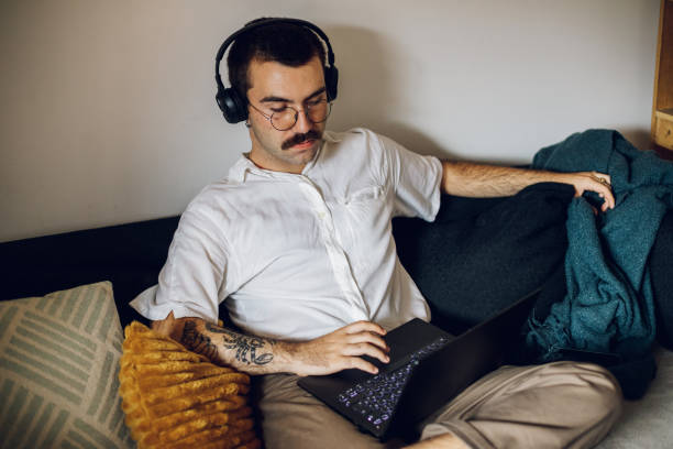 istock Man with a mustache working on laptop at home and using headphones 1431359644