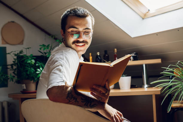 istock Fashionable hipster man with mustache reading a book while at home. 1431359651