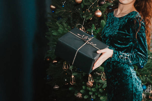 istock Woman holding a gift box near Christmas tree 1431359745