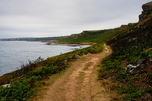 Wide, winding coastal footpath leading to Port Eynon on a gloomy summer day.