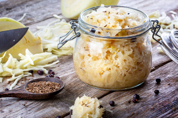 Homemade sauerkraut with cumin and juniper berries in a glass jar, closeup