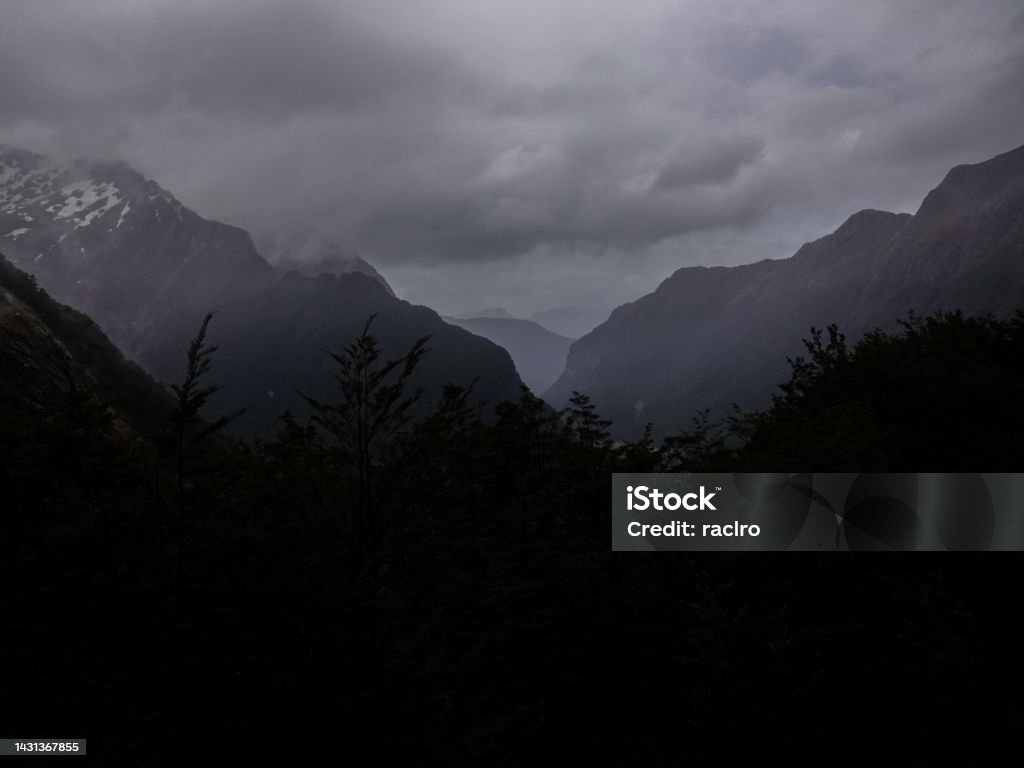 Looking down the cloud filled dark valley from high above in heavy rainfall. Routeburn Track, Mount Aspiring National Park, New Zealand. Dark Stock Photo