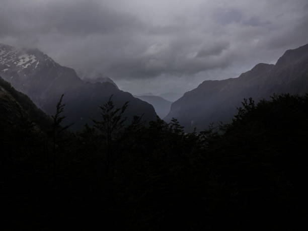 Looking down the cloud filled dark valley from high above in heavy rainfall. Routeburn Track, Mount Aspiring National Park, New Zealand. stock photo