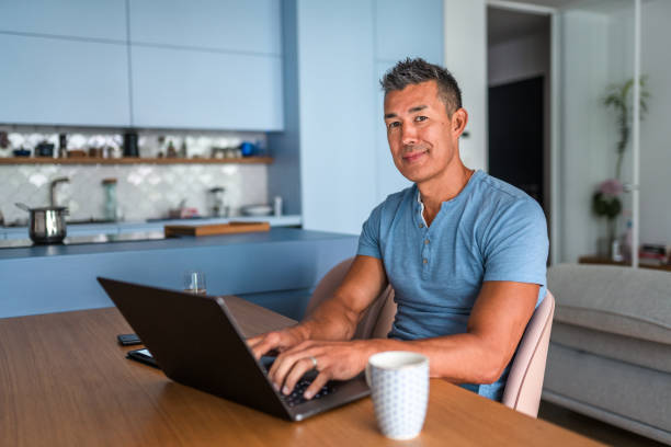 istock Japanese Man Looking At Camera And Working On Laptop At Home 1431368104