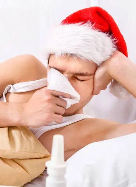 Sick Man in Santa Hat with a Handkerchief in the Bed closeup