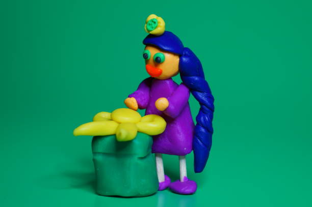 istock A plasticine toy girl with a gift on a green background. 1431375793