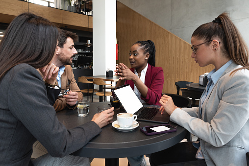 Four young people making their online business for shopping booking and restaurant reservation as internet app service. Friends working on plans and ideas for their new small company.