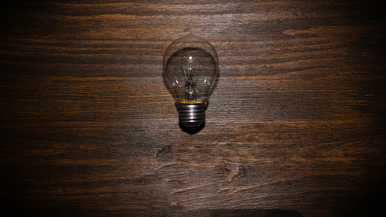 Light bulb is off.  Energy concept with light bulb on brown wooden background with copy space