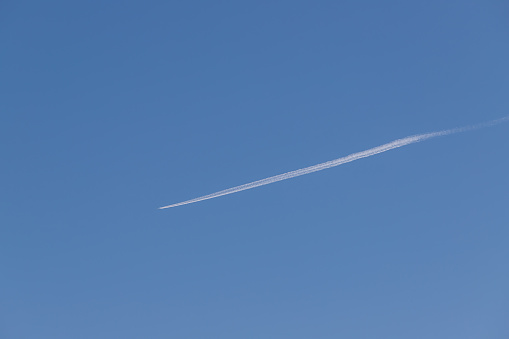 Airliner flies high in the sky. There is a line behind the plane.